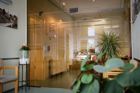 Wartezimmer hinter einer Glaswand, mit Stühlen und Pflanzen